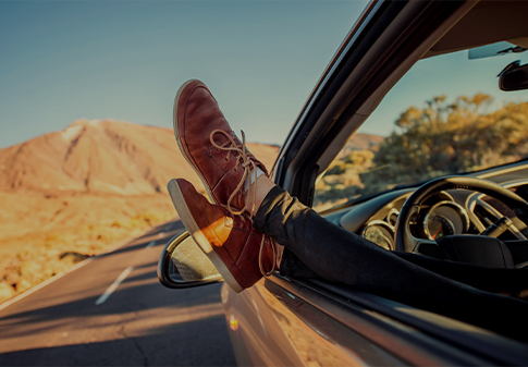 feet crossed rested on the car door