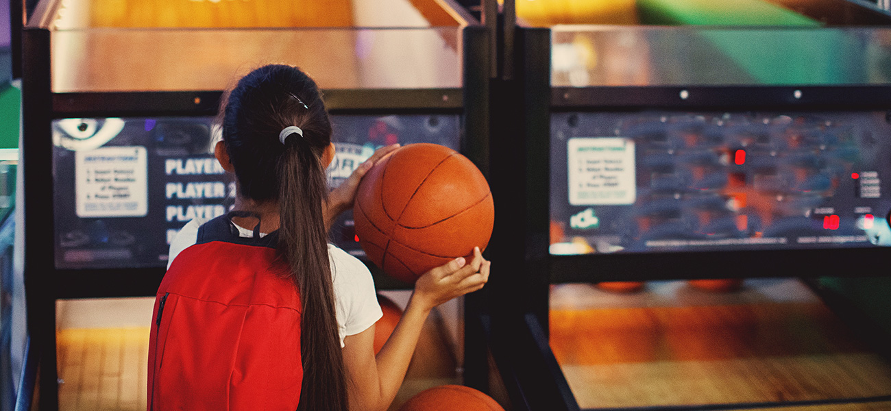 Kid playing basketball game at an arcade.